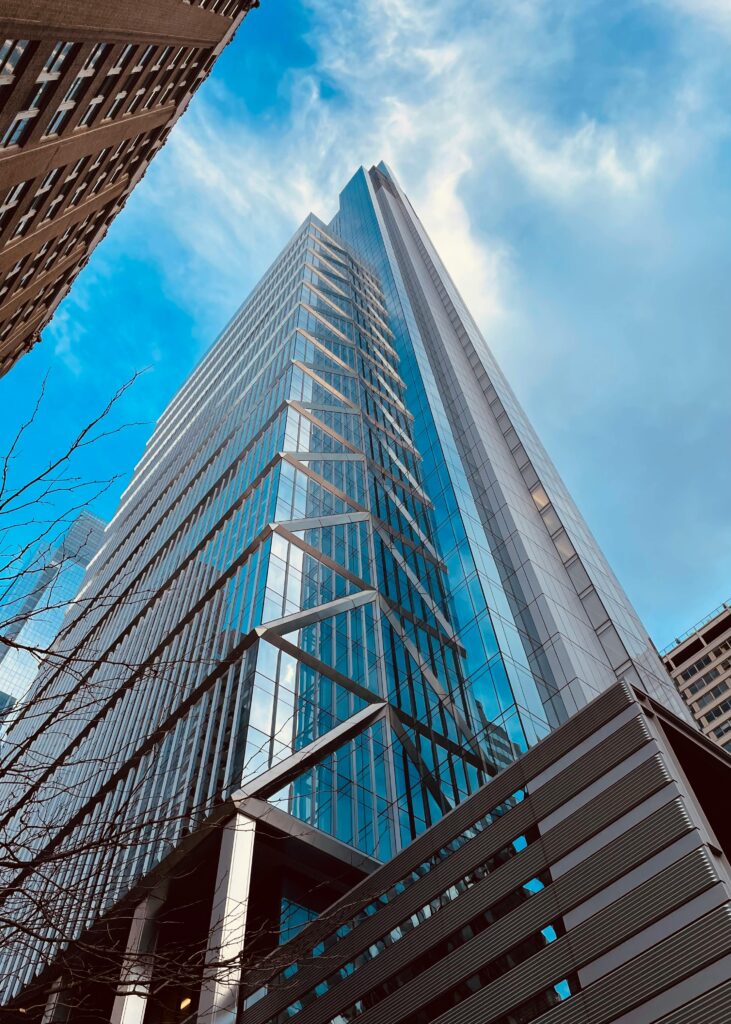 Looking up at a modern glass skyscraper against a blue sky.